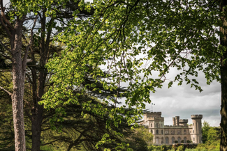 Sunny view of Eastnor Castle over the lake