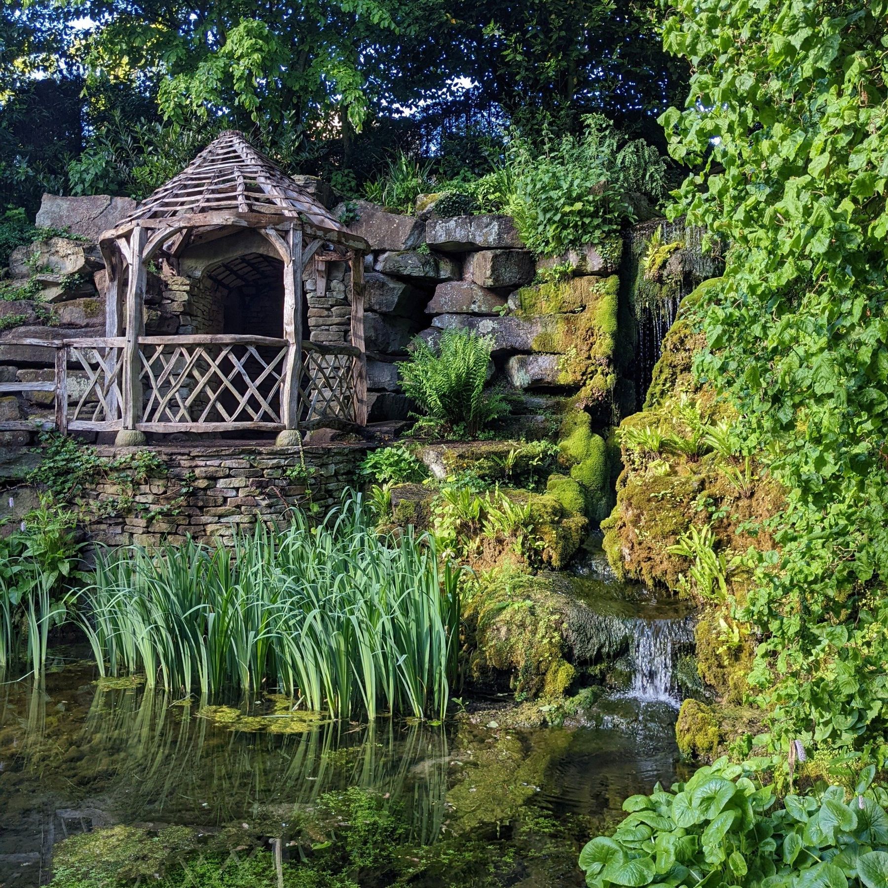 View of the sucken garden with the pond in the foreground and wooden lake side hut