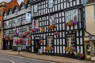 Large black and white historic hotel with hanging baskets of flowers