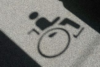 Shadow of a wheelchair symbol appears on a floor