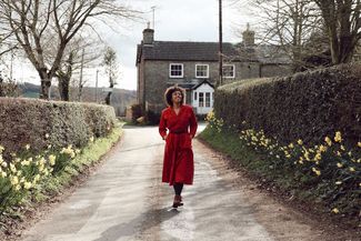 A woman wanders down a daffodil lined street