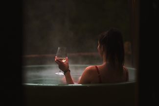 A woman sips wine in a hot tub