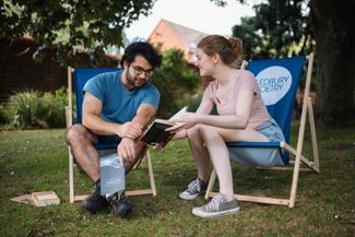 couple sat on deckchairs reading a book at Ledbury Poetry festival