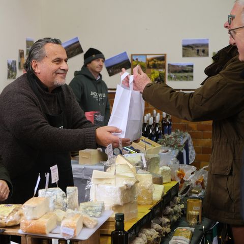 Gentleman handing a bag of cheese to customer