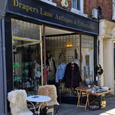 Exterior of antique shop with chairs outside draped in sheepskin rugs