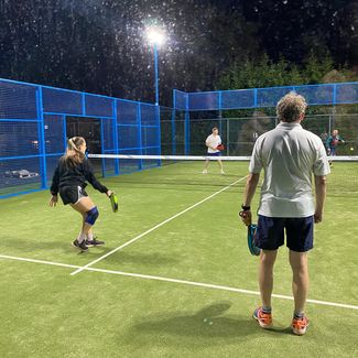 Group playing Paddle on flood lit court