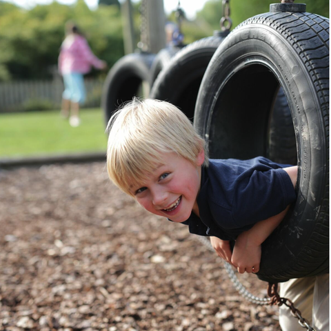 Boy poking his head through a tyre on the obstacle course