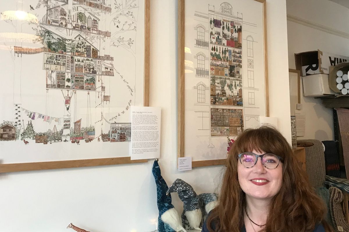 lady with glasses in front of framed artwork on the wall