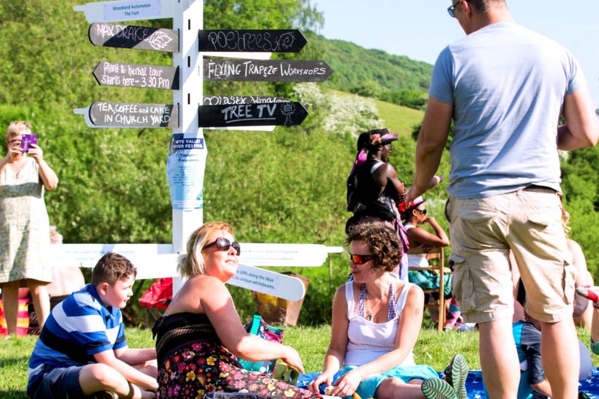 Group sit in a scenic sunny spot by the signs