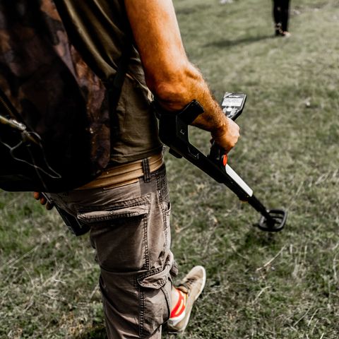 Man metal detecting in a field 