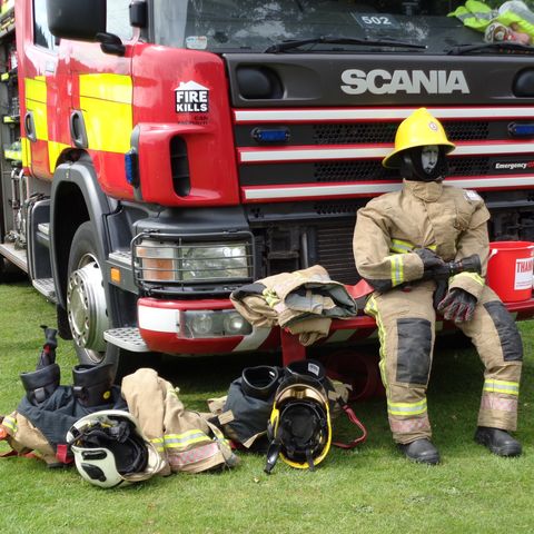Scarecrow of a firefighter sat in front of a fire engine 