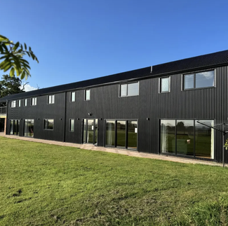 Large black barn conversion on blue sky day 