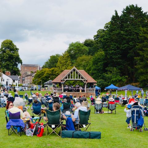 An open-air music event with people watching acts on a bandstand in Ross-on-Wye