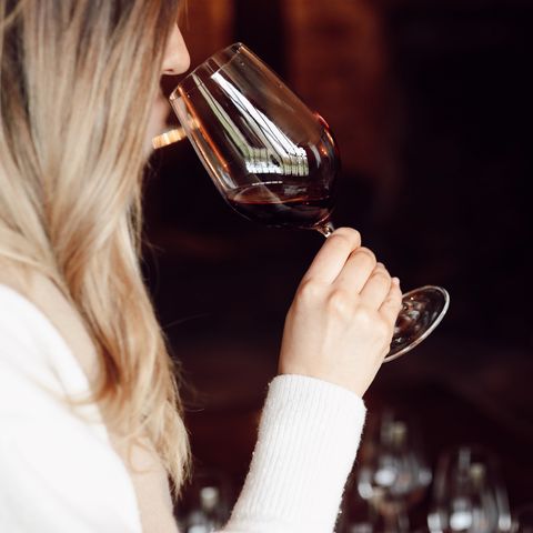 woman tasting red wine in dark room