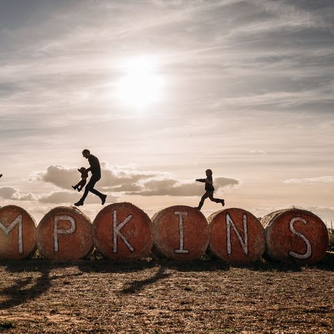family jumping over round bales