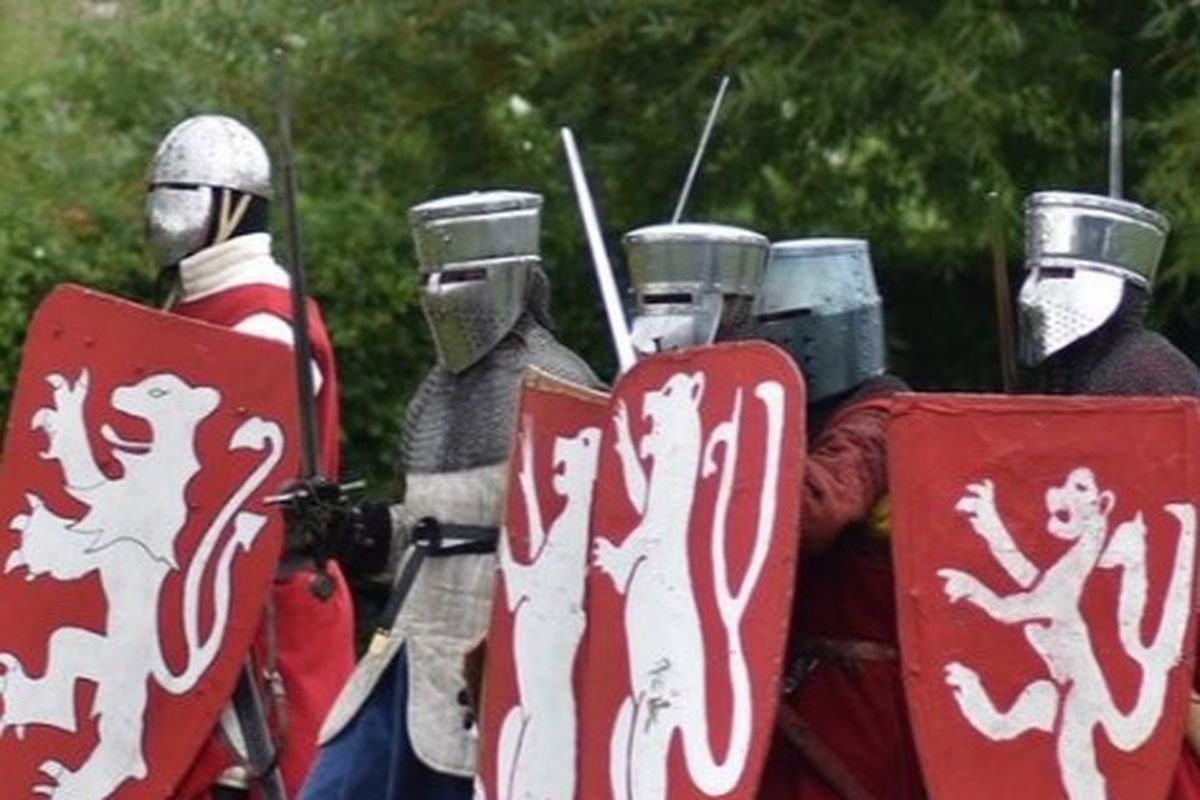 people dressed as knights in silver helmets with red shields and twin tailed lion crest