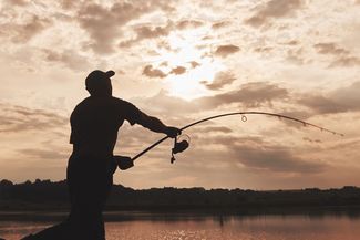 Silhouette of man fishing over lake