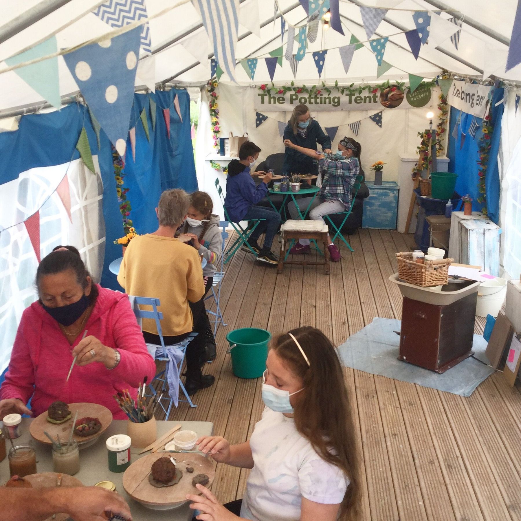 Families making clay models in the Potting Tent Marquee at Eastnor Pottery