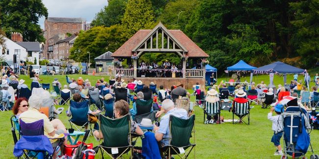 An open-air music event with people watching acts on a bandstand in Ross-on-Wye
