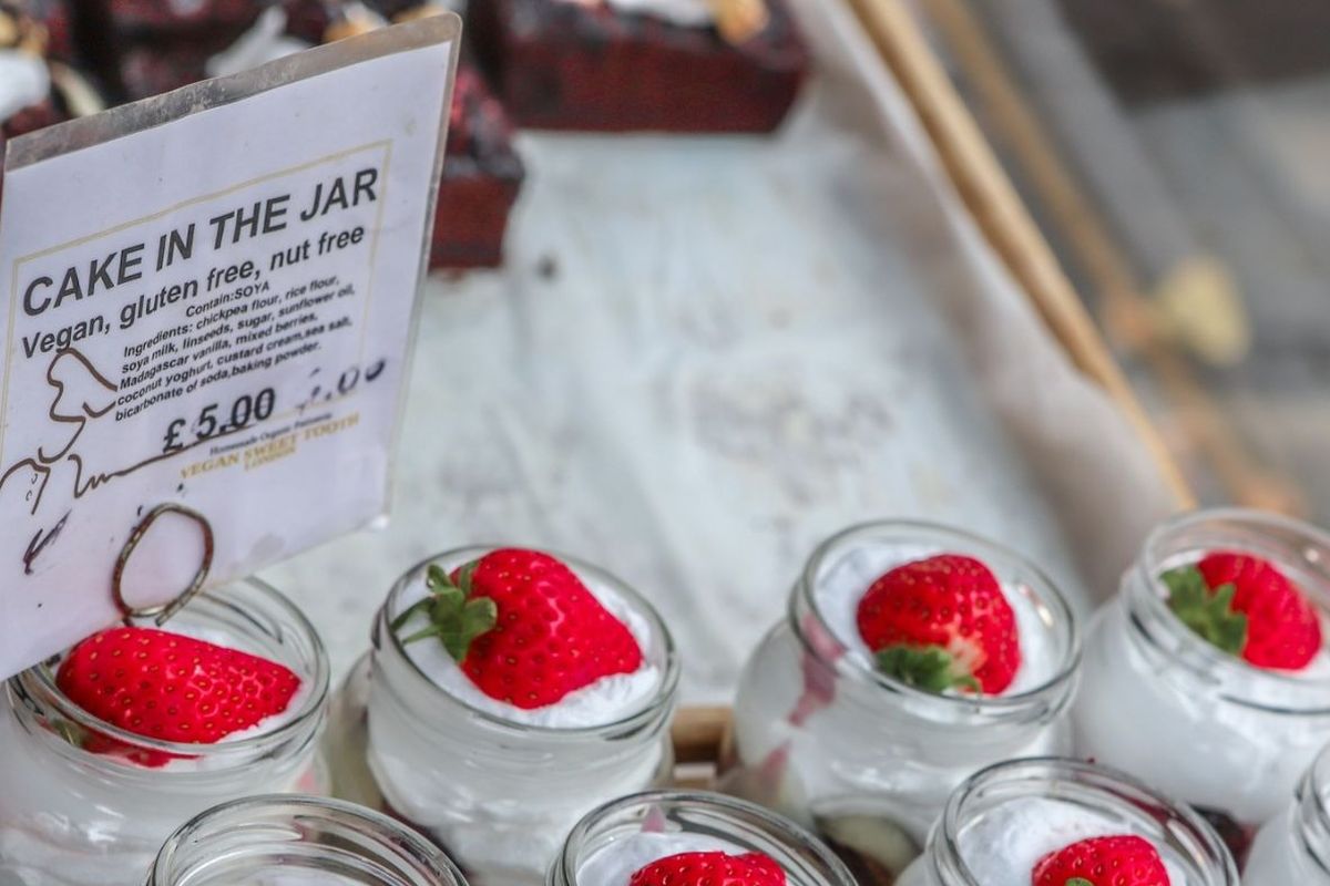 Vegan Cakes in a jar, delicous looking layers with cream and a strawberry on top