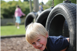 Boy poking his head through a tyre on the obstacle course