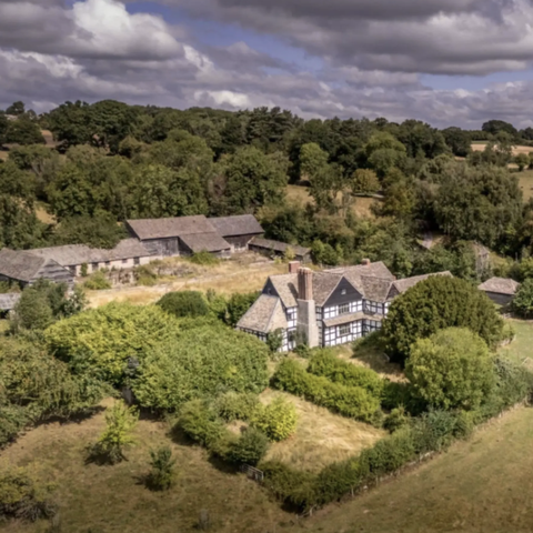 Tudor farmhouse surrounded by woodland and open fields