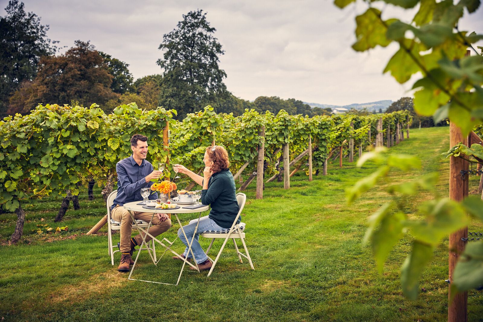 couple sitting at a table with wine in a vineyard