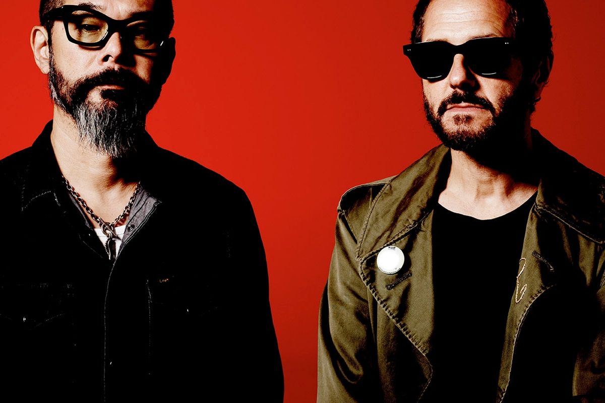 two band members in black against red background