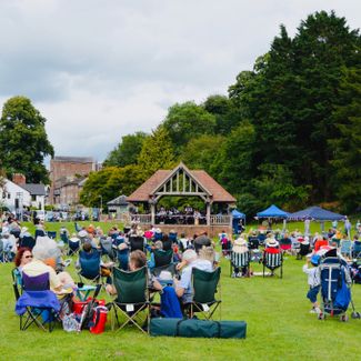 An open-air music event with people watching acts on a bandstand in Ross-on-Wye