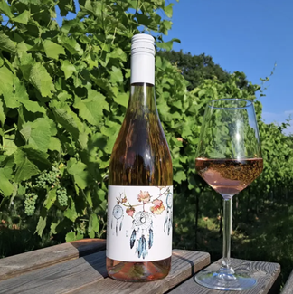 bottle of rose wine next to a full glass with blue sky