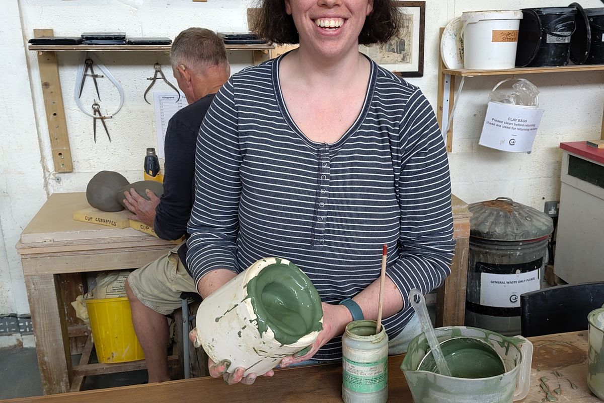 Lady holding a pot with grey clay slip