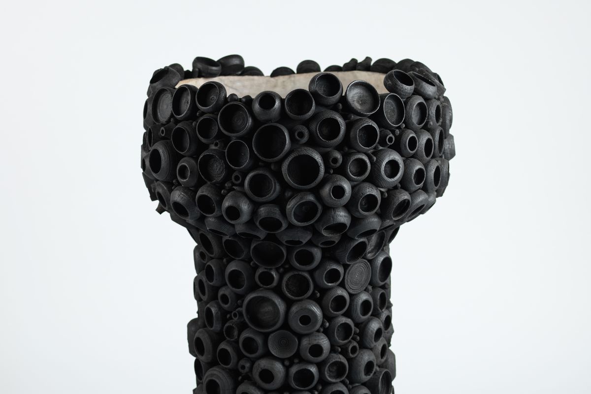 sculpture with black cup-like shapes all over the outside
