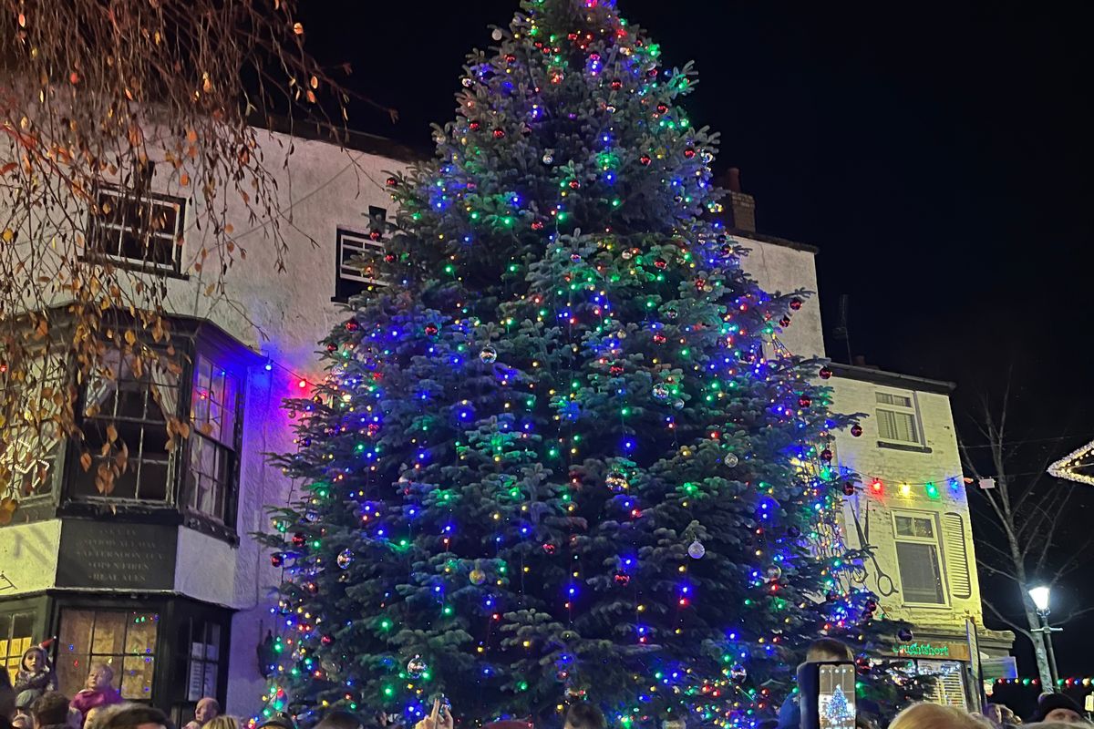 large decorated Christmas tree in town square with crowds