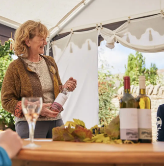 Woman holding out a bottle of wine in a marquee