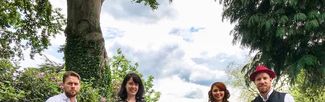 The four members of The Kilpecks standing on a country lane with their musical instruments