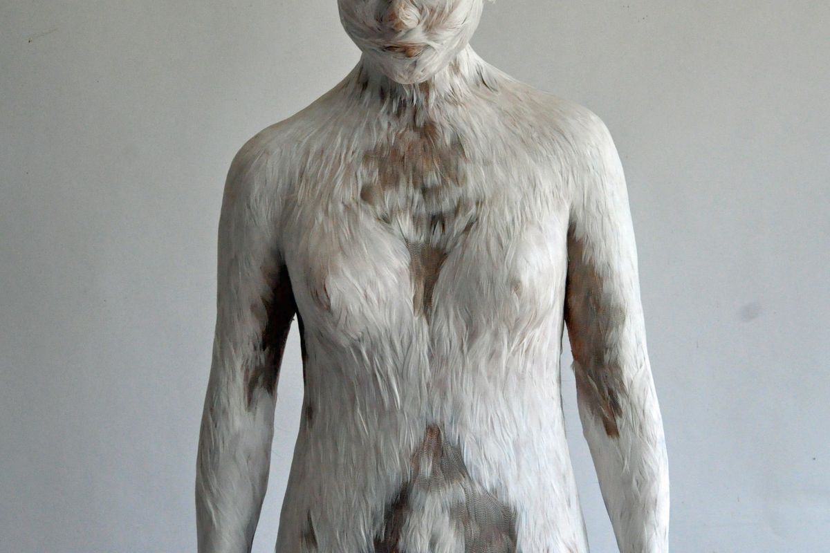 sculpture of figure with feather-like texture on surface