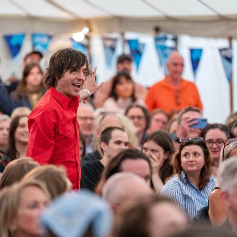 A person giving a presentation in a marquee full with a seated audience 