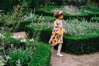 Little girl running around the flower beds at Hampton Court