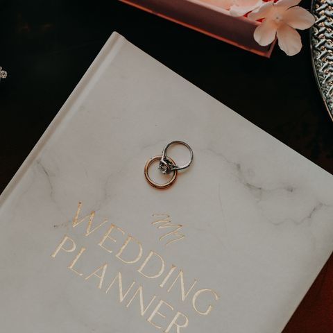 Wedding Planner note book and wedding rings laid on top